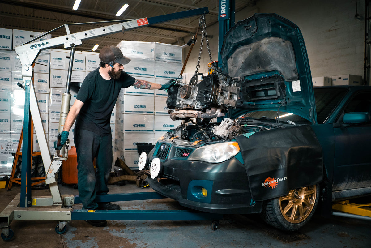 Technician lowering an engine into a Subaru with a hoist at the OAKOS service shop, Sterling Heights, MI